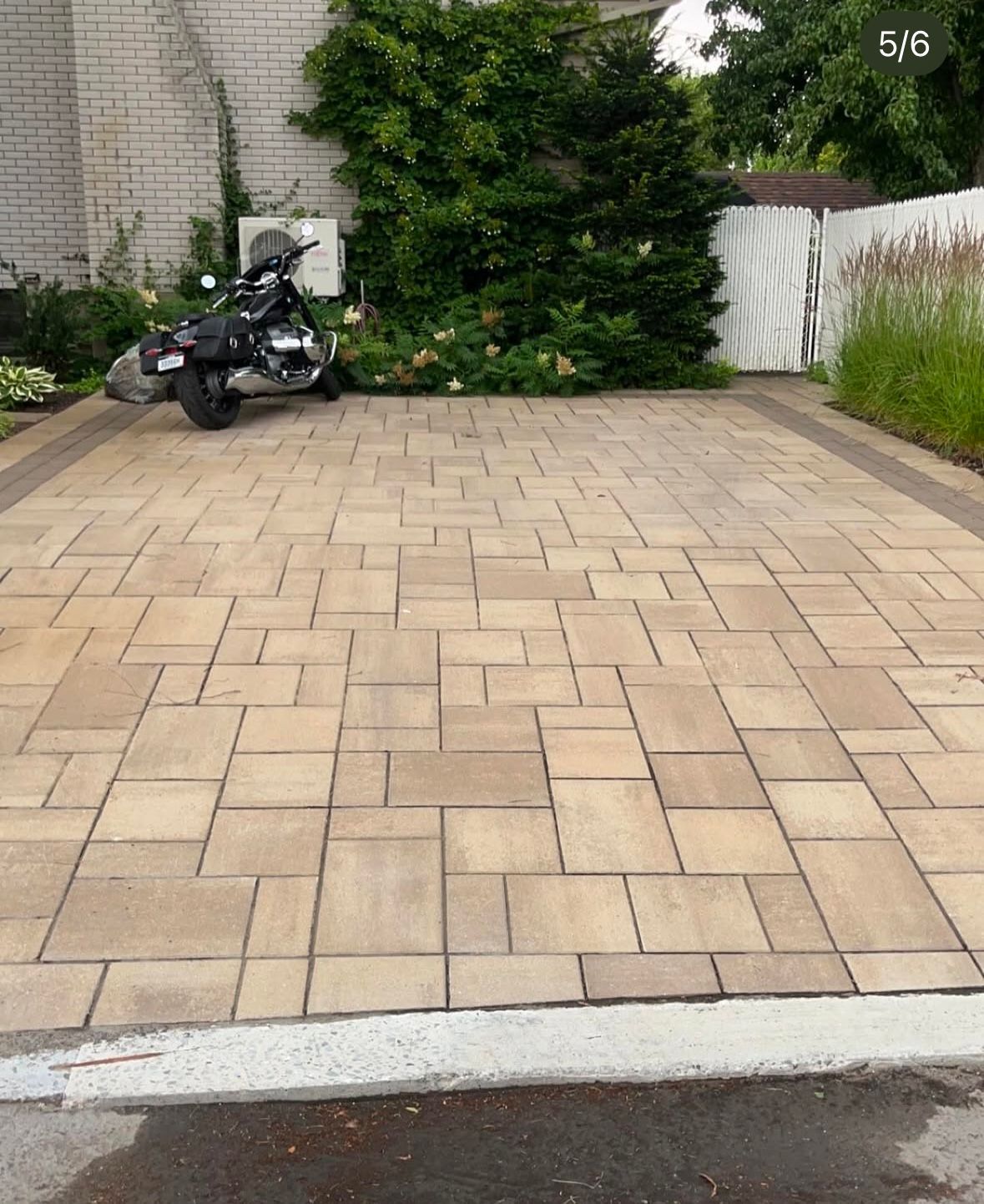 Une moto est garée dans une allée à côté d'une maison.