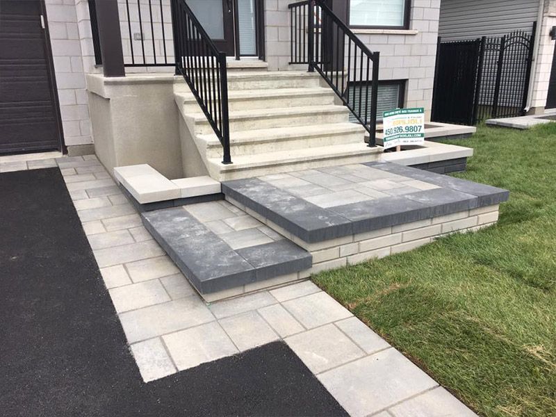 Un escalier menant à une maison avec une rampe noire.
