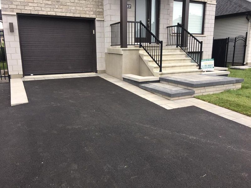 Une maison avec une porte de garage noire et des escaliers