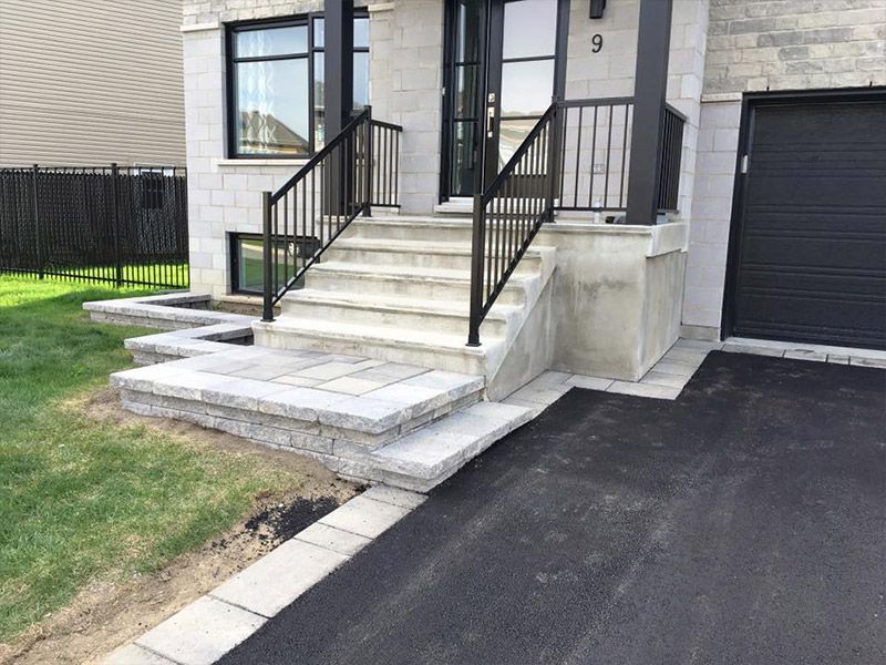 Une maison avec des escaliers et une porte de garage noire