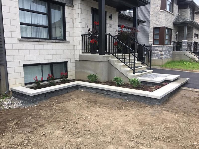 Une maison avec des escaliers et une jardinière devant.