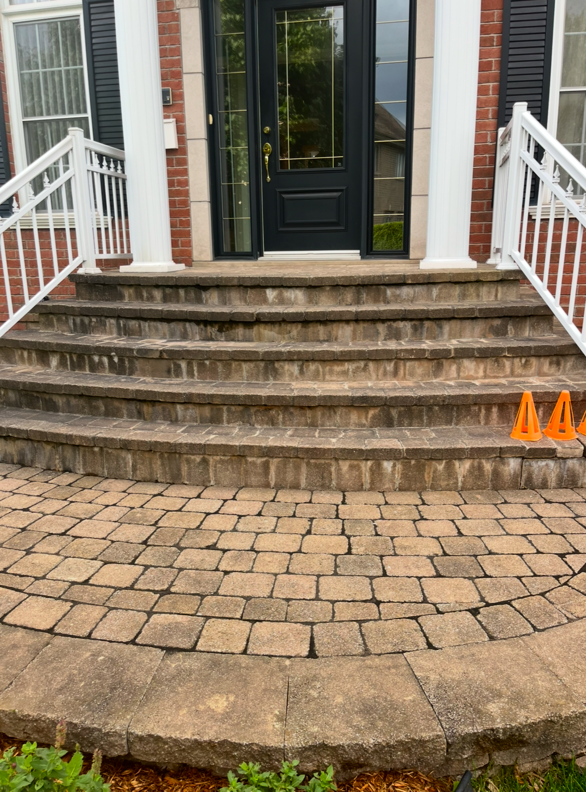 Un patio en briques avec des escaliers menant à la porte d'entrée d'une maison.