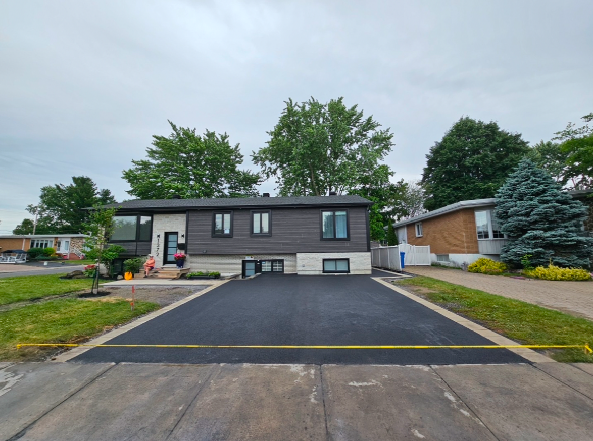 Une maison avec une allée nouvellement pavée devant elle.