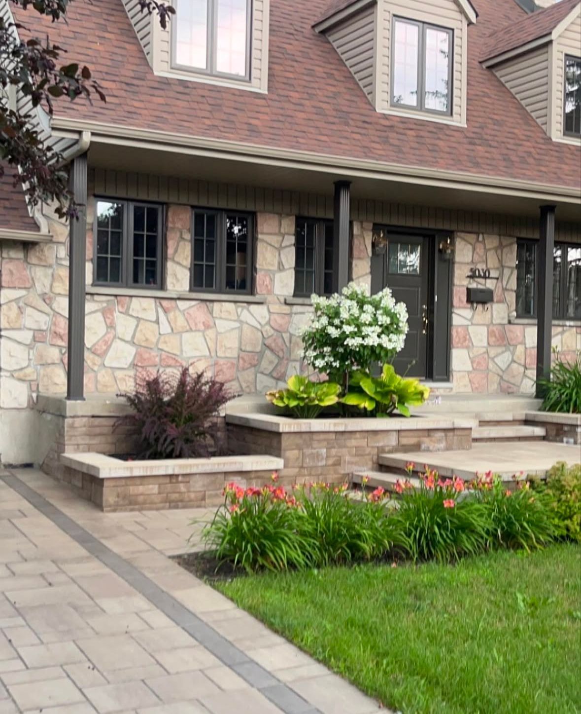 La façade d'une maison avec un porche et des fleurs devant