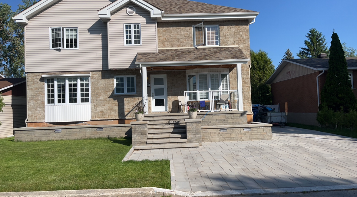 Une grande maison en briques avec une allée devant.