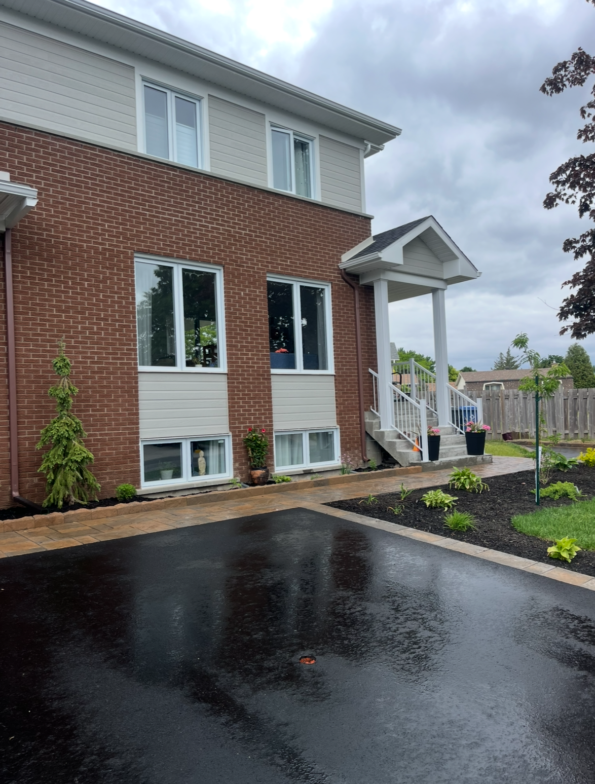 Une maison en briques avec une allée noire devant elle