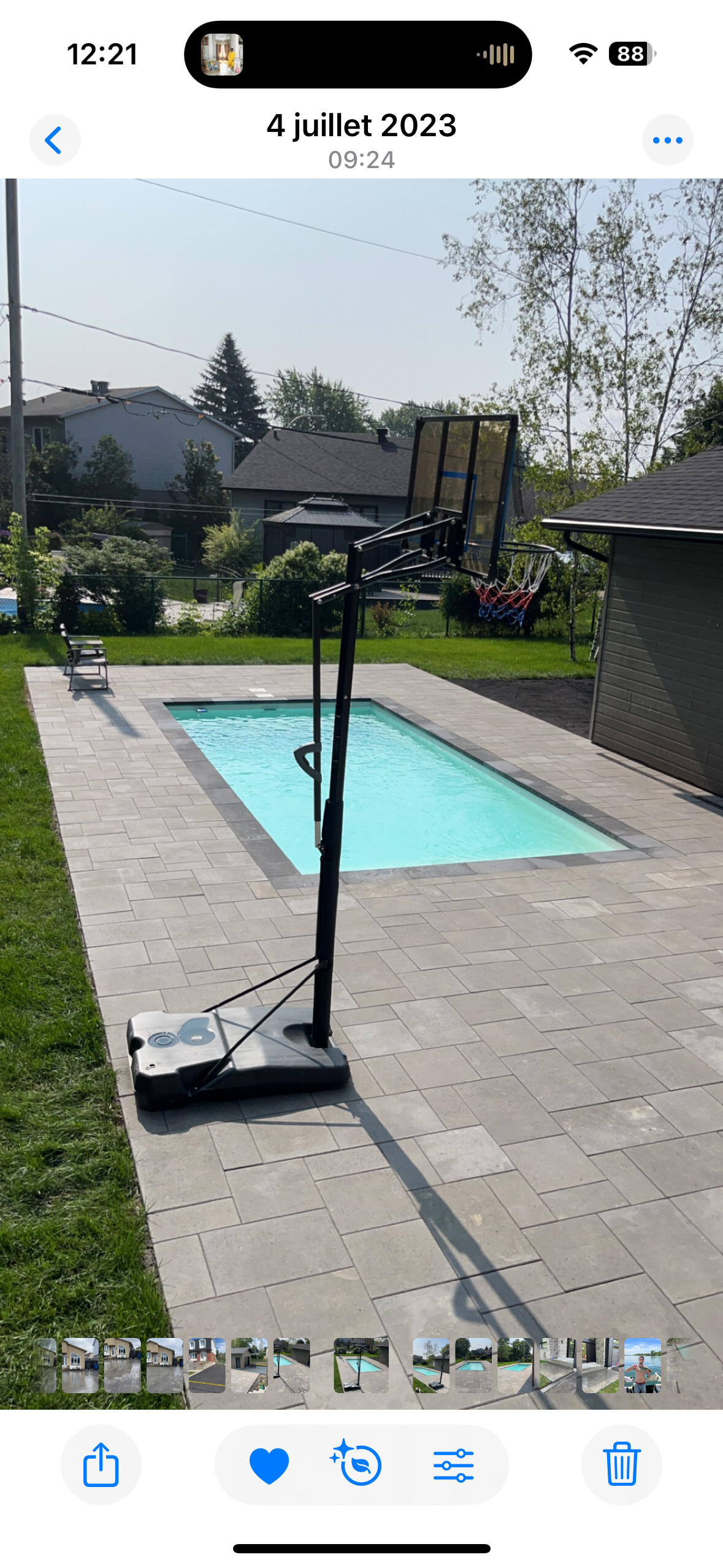 Un panier de basket est assis à côté d'une piscine dans un jardin.