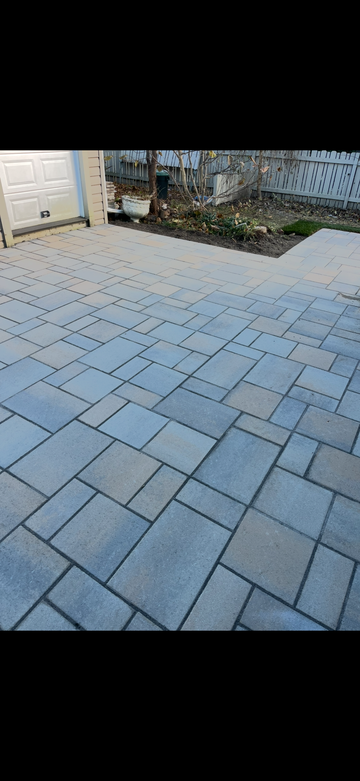 Un patio avec une allée en briques menant à un garage.