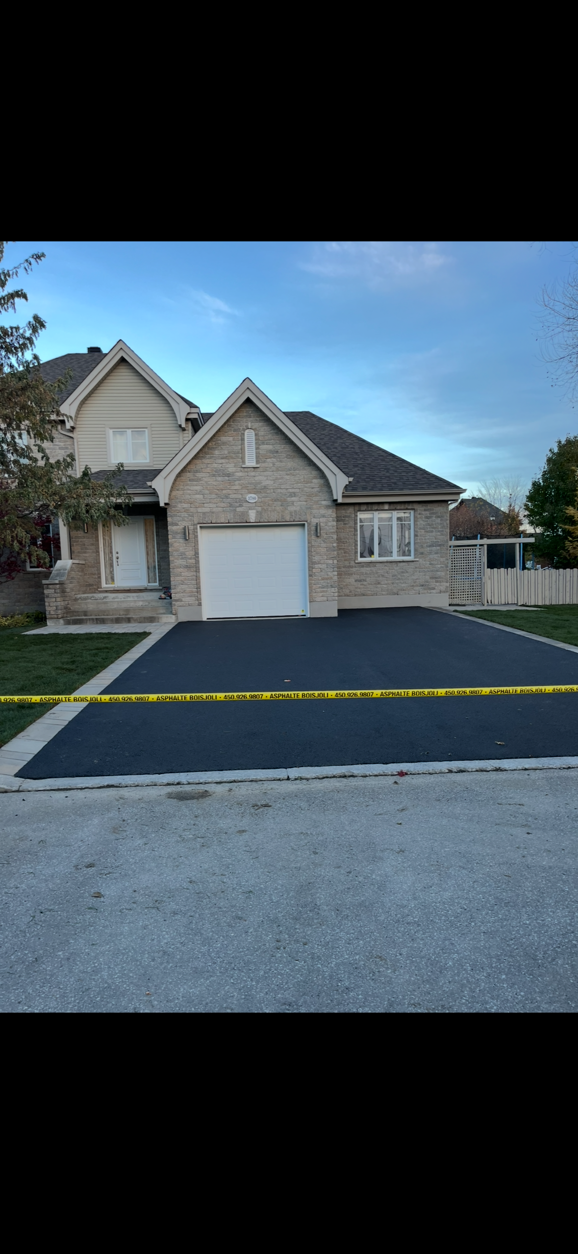 Une maison en briques avec une allée noire devant elle.