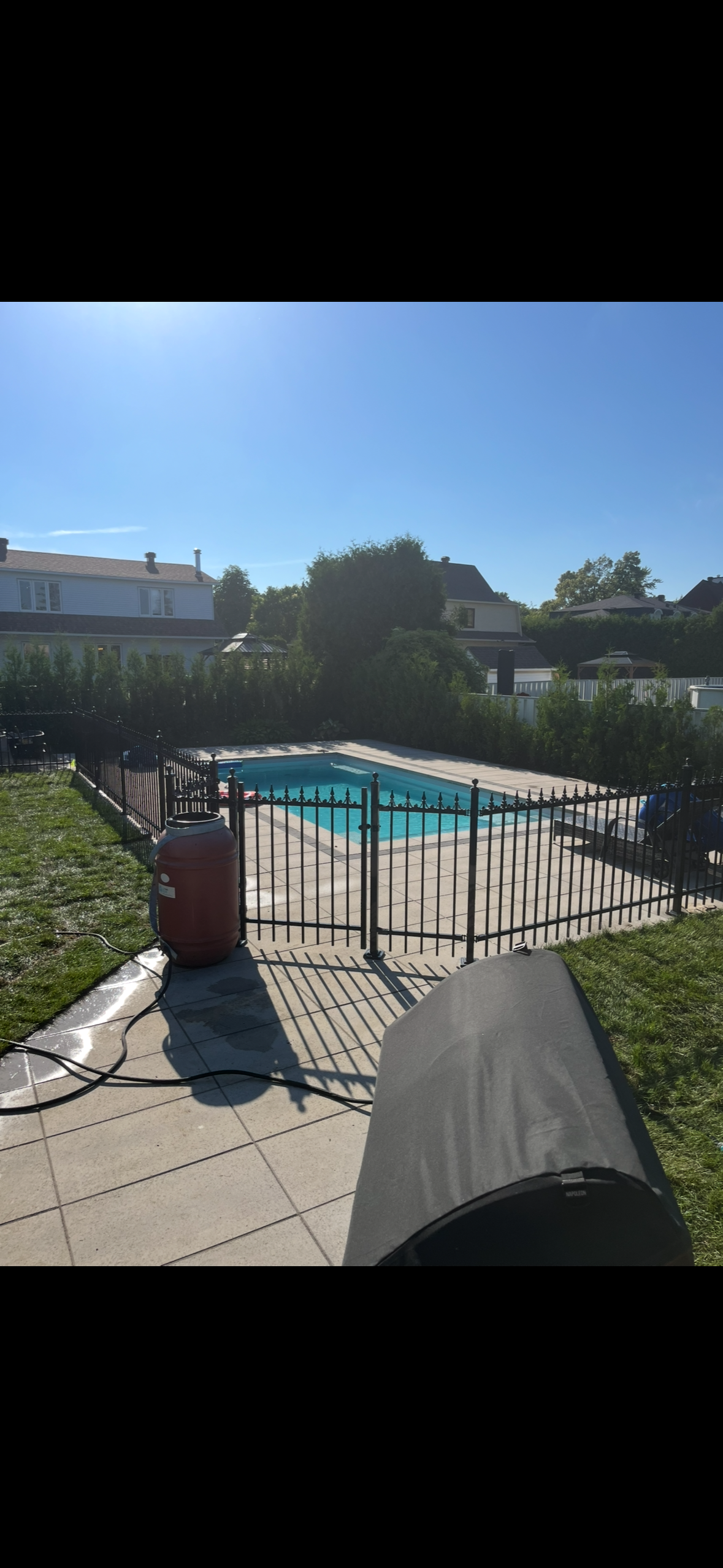 Une grande piscine est entourée d'une clôture dans une cour arrière.