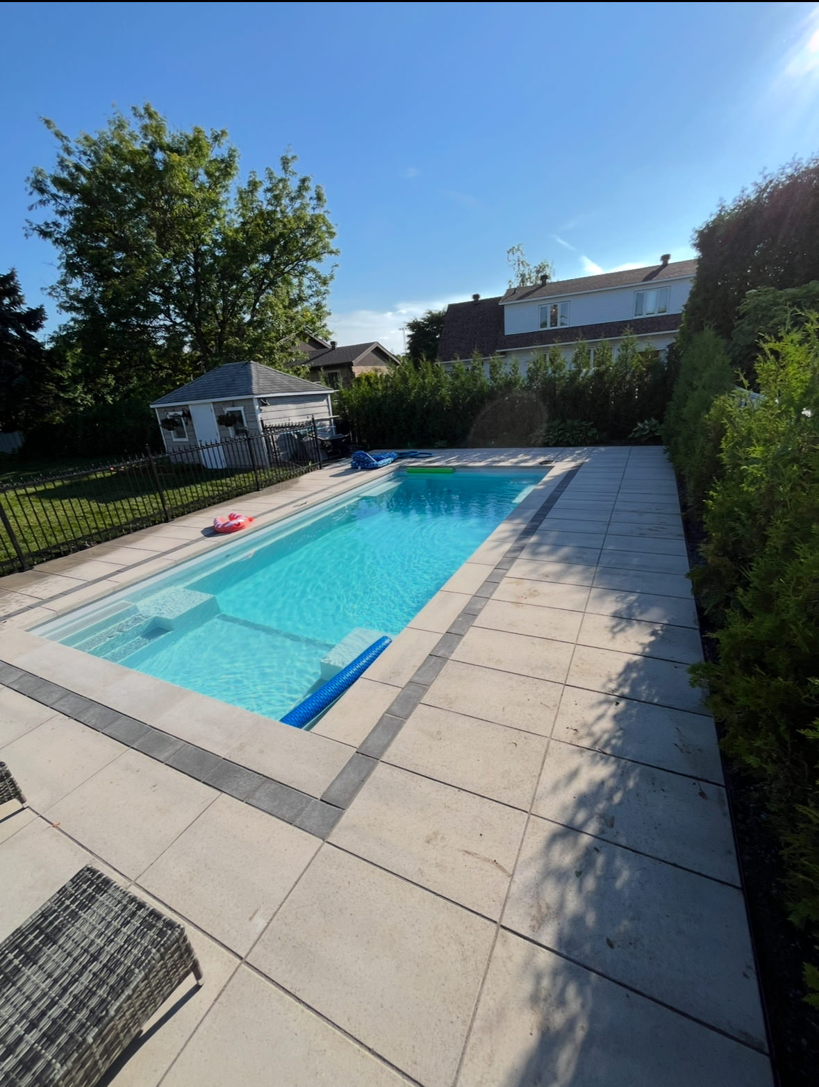 Une grande piscine dans une cour arrière avec une maison en arrière-plan