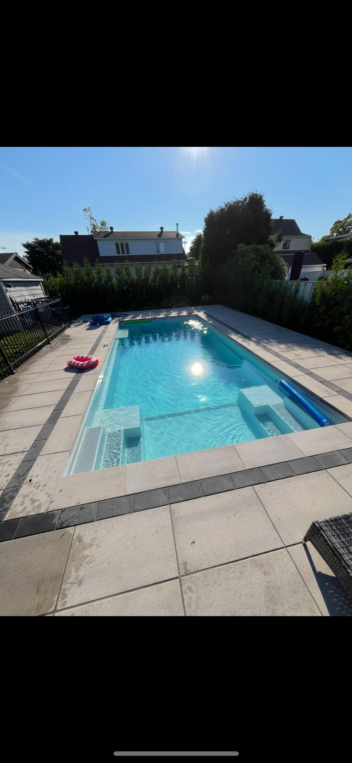 Il y a une grande piscine dans l'arrière-cour d'une maison.