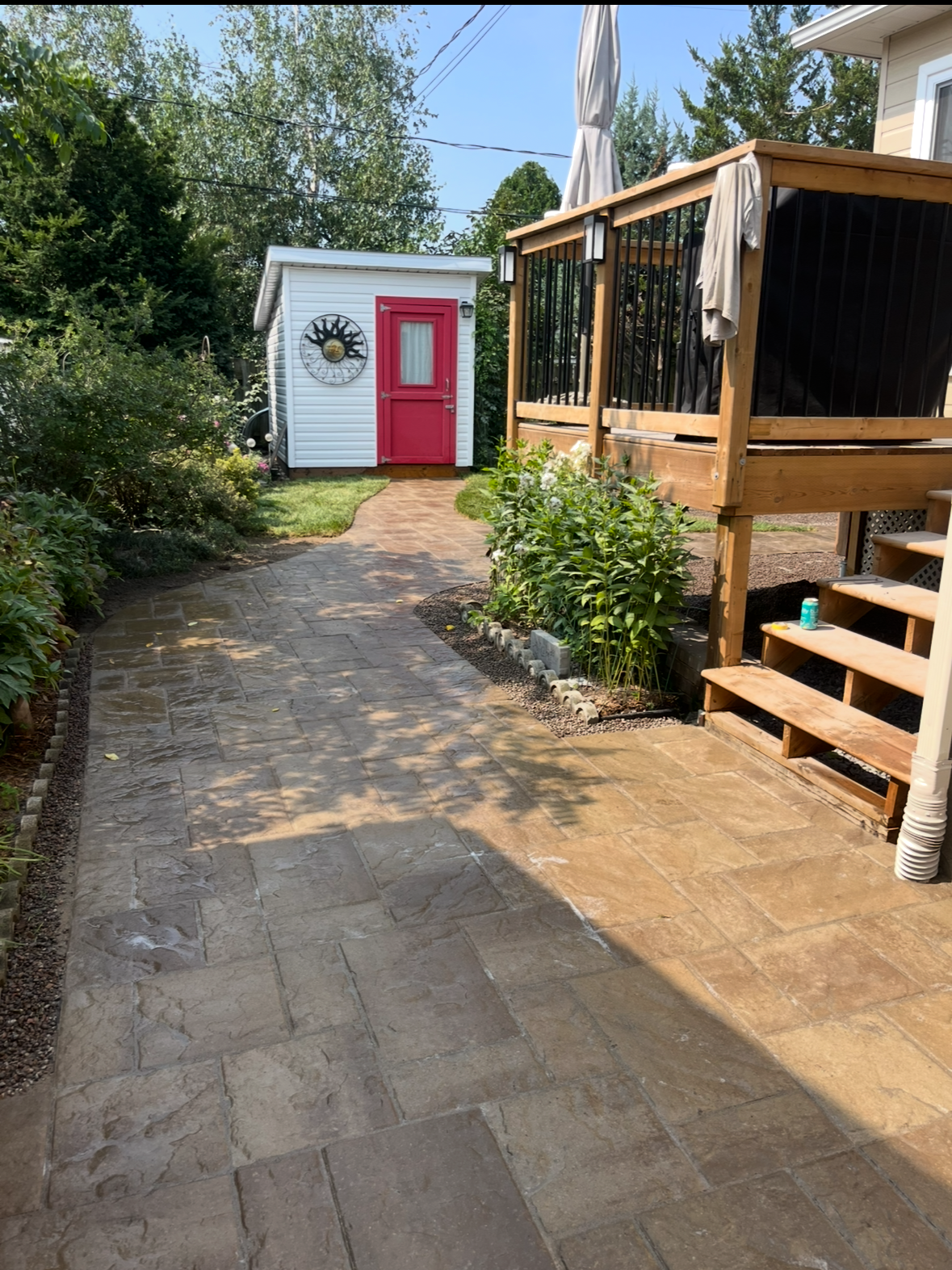 Une passerelle menant à un hangar avec une porte rouge et une terrasse.