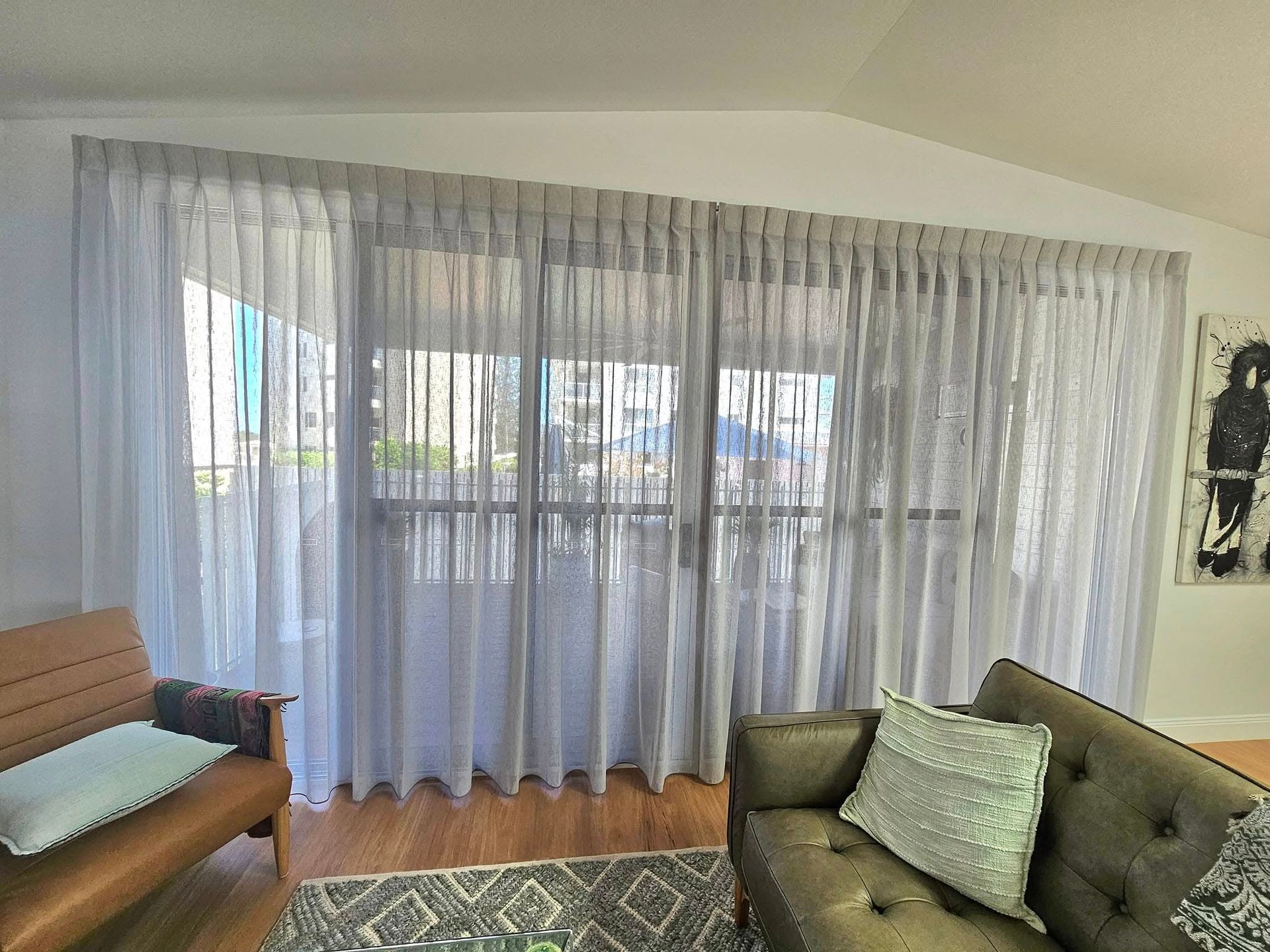 A window covered with sheer cream-colored curtains. The curtains are slightly drawn back, revealing the window and some light. — Modern Window Furnishings In Woodgate, QLD