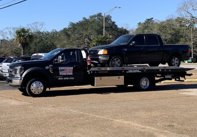 A black truck is being towed by a tow truck