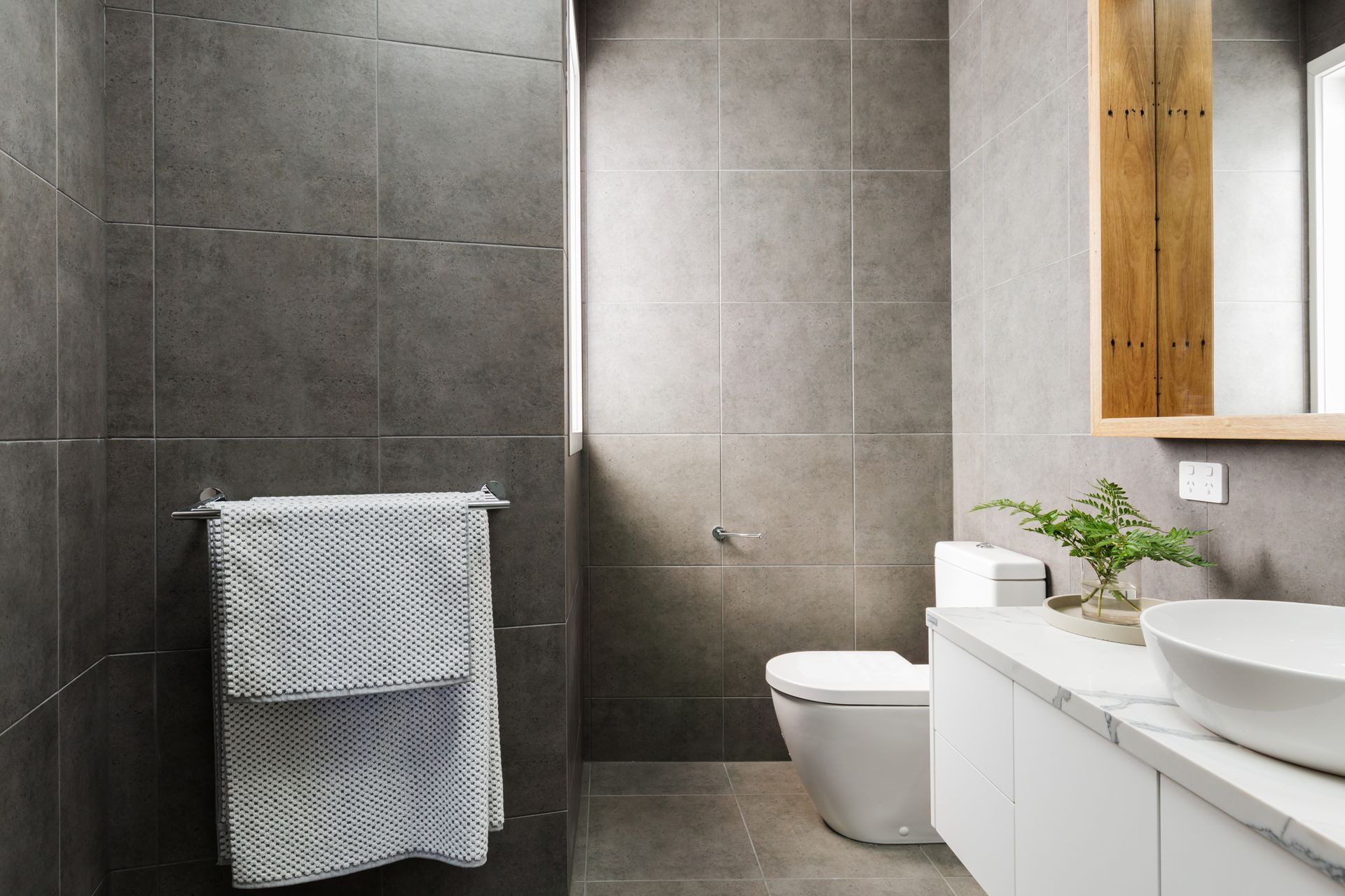 A bathroom with a toilet , sink and mirror.
