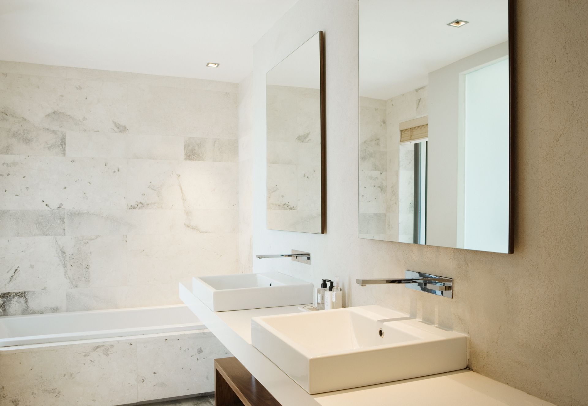 A bathroom with two sinks , a mirror and a bathtub.