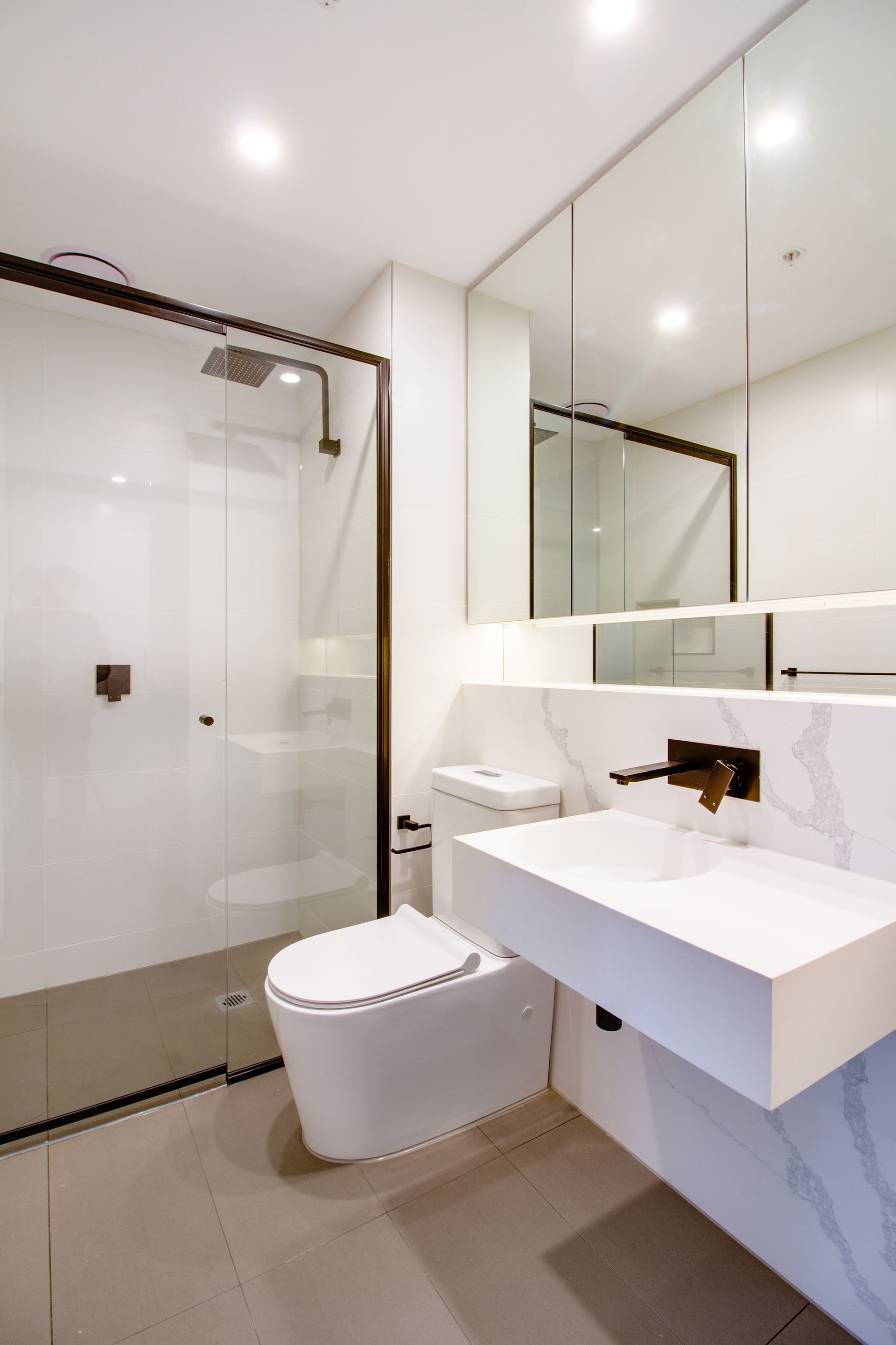 A bathroom with a toilet , sink , shower and mirror.