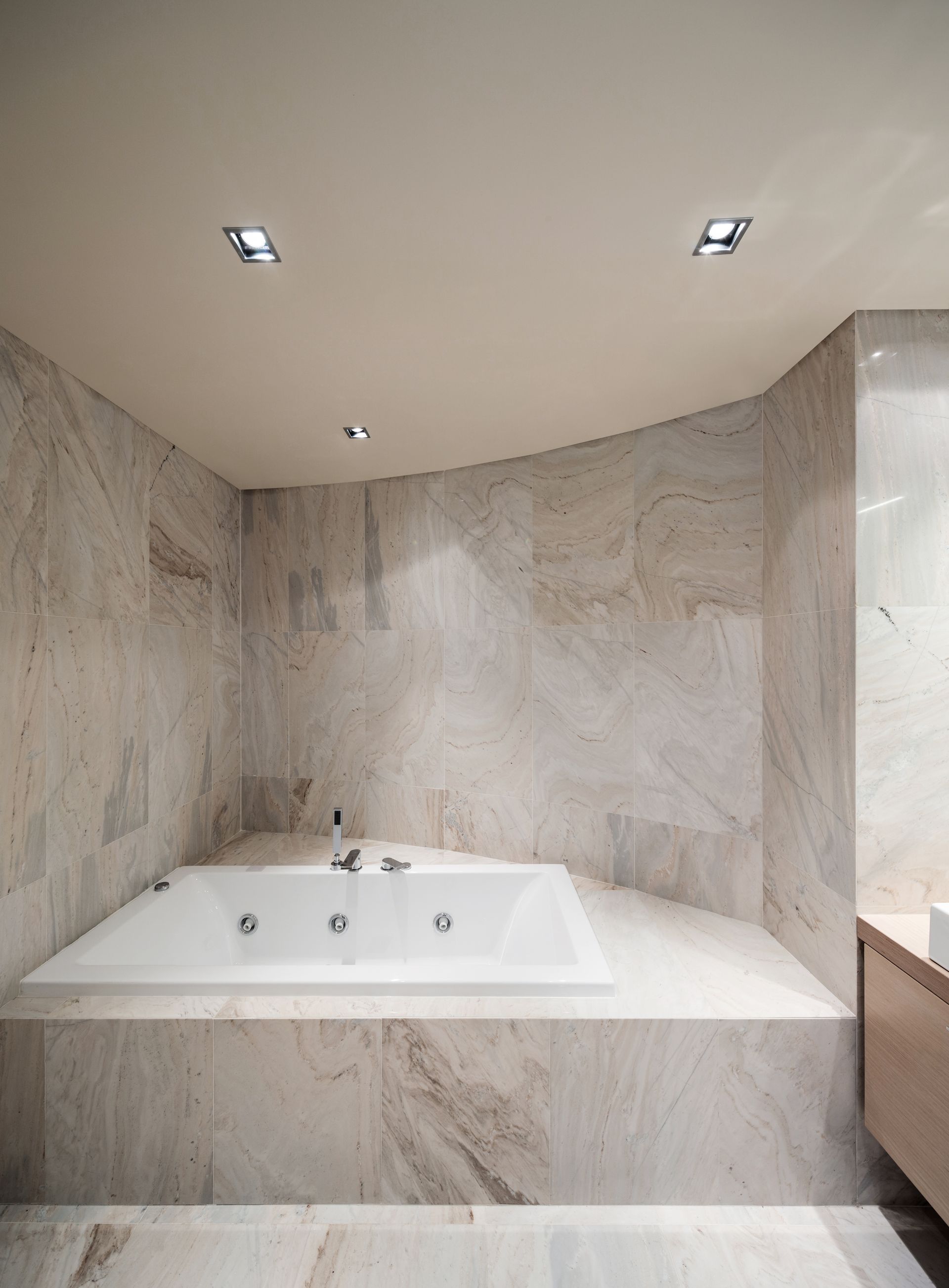 A bathroom with a spa bath and marble walls.