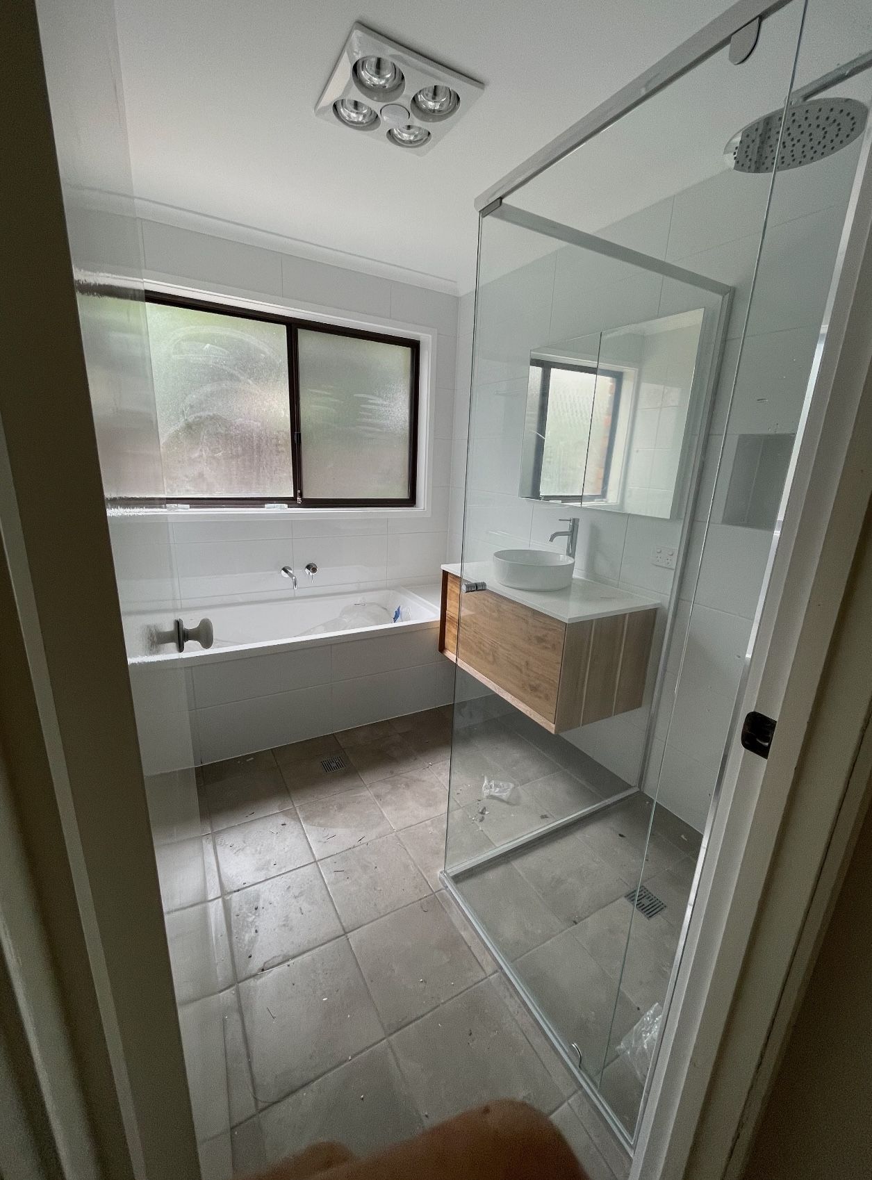 A bathroom with a bathtub , sink , shower and window.