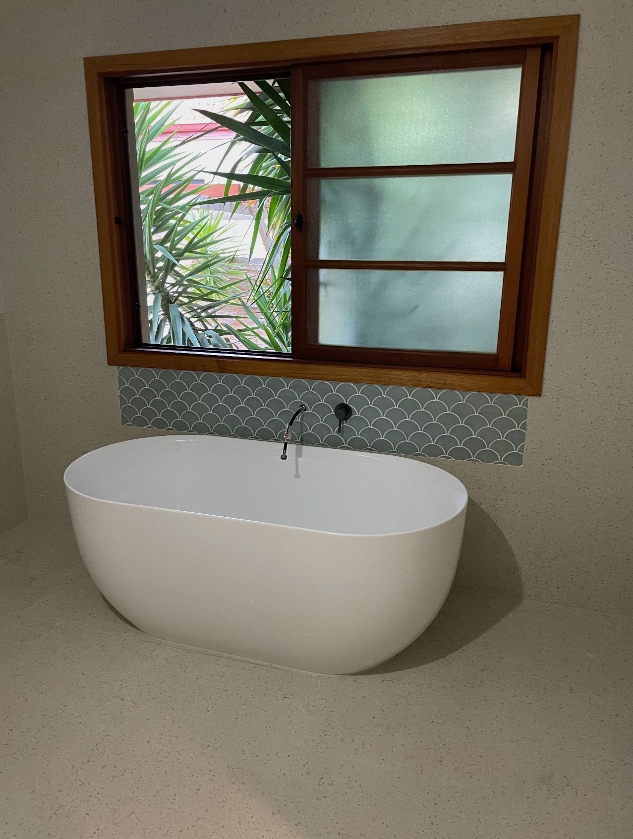 A bathtub in a bathroom next to a window.