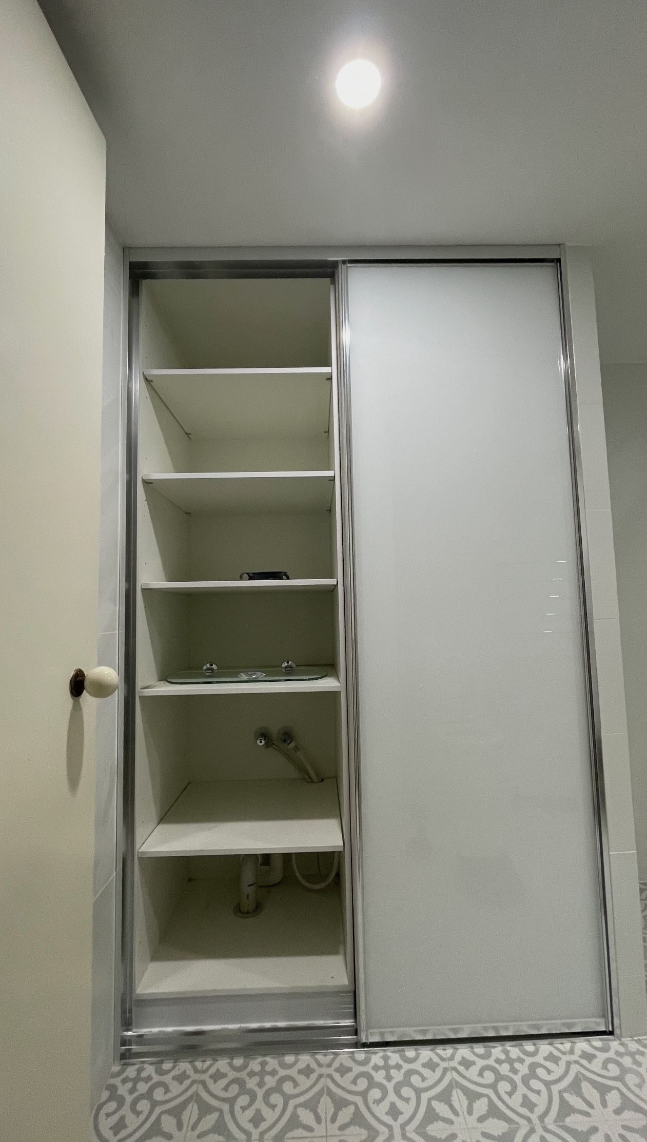 A white closet with sliding doors and shelves in a hallway.