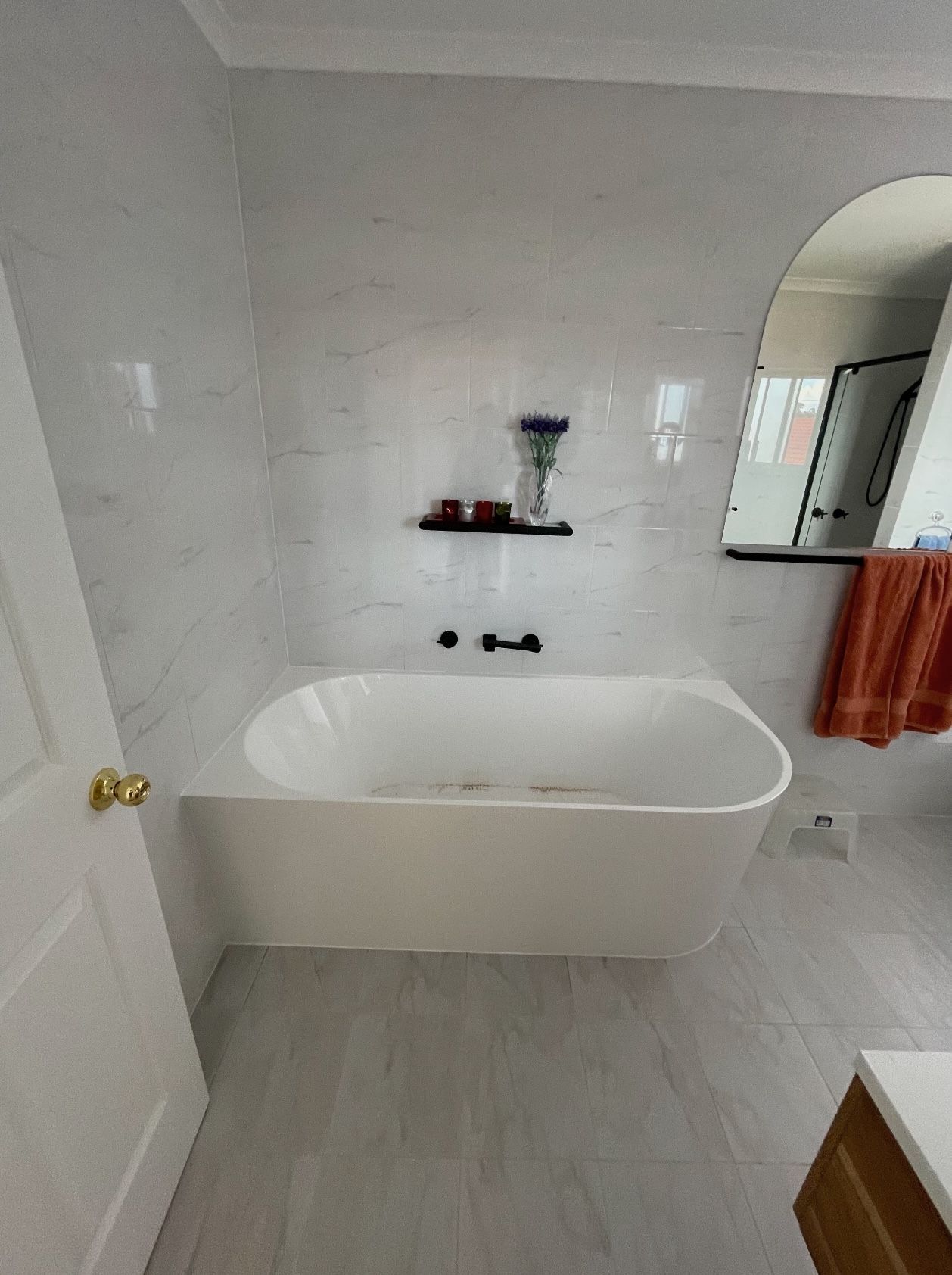 A bathroom with a bathtub and a mirror.