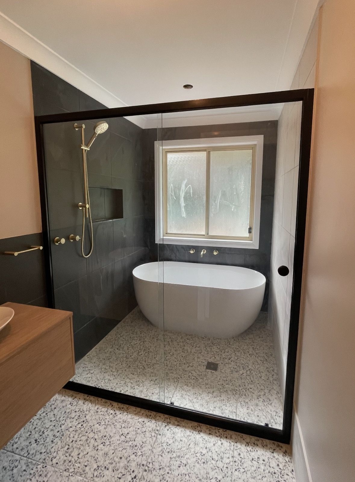 A dark tiled bathroom with a bathtub and a shower stall.