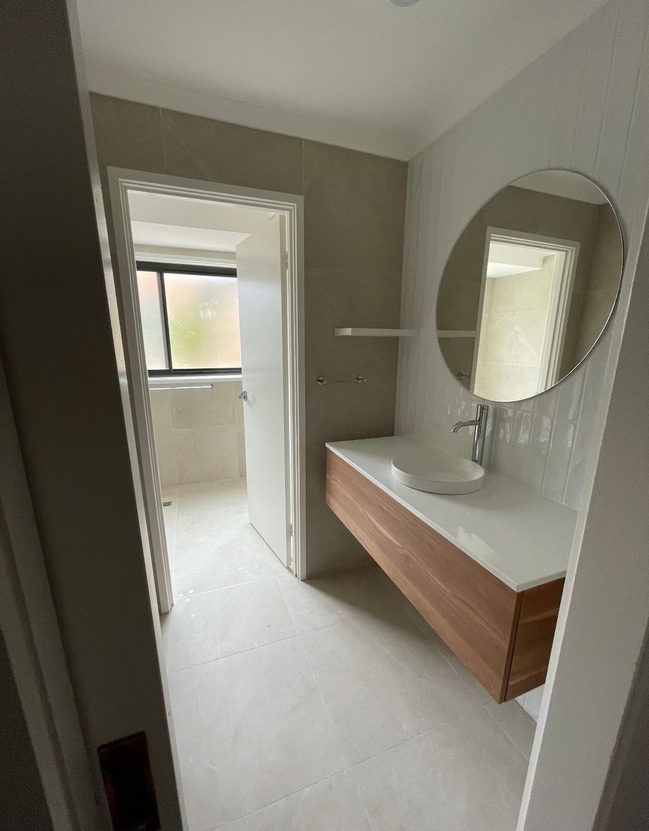 A bathroom with a sink , mirror and window.