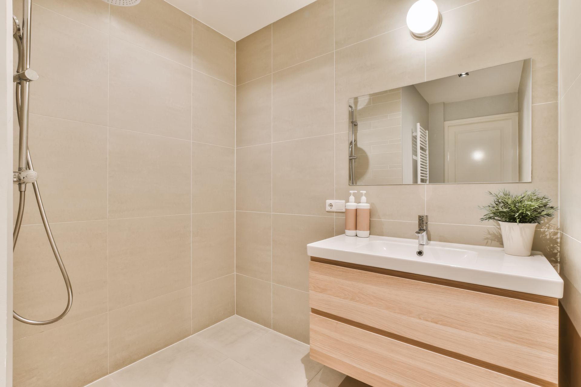 A bathroom with a sink , beige vanity , mirror and shower.