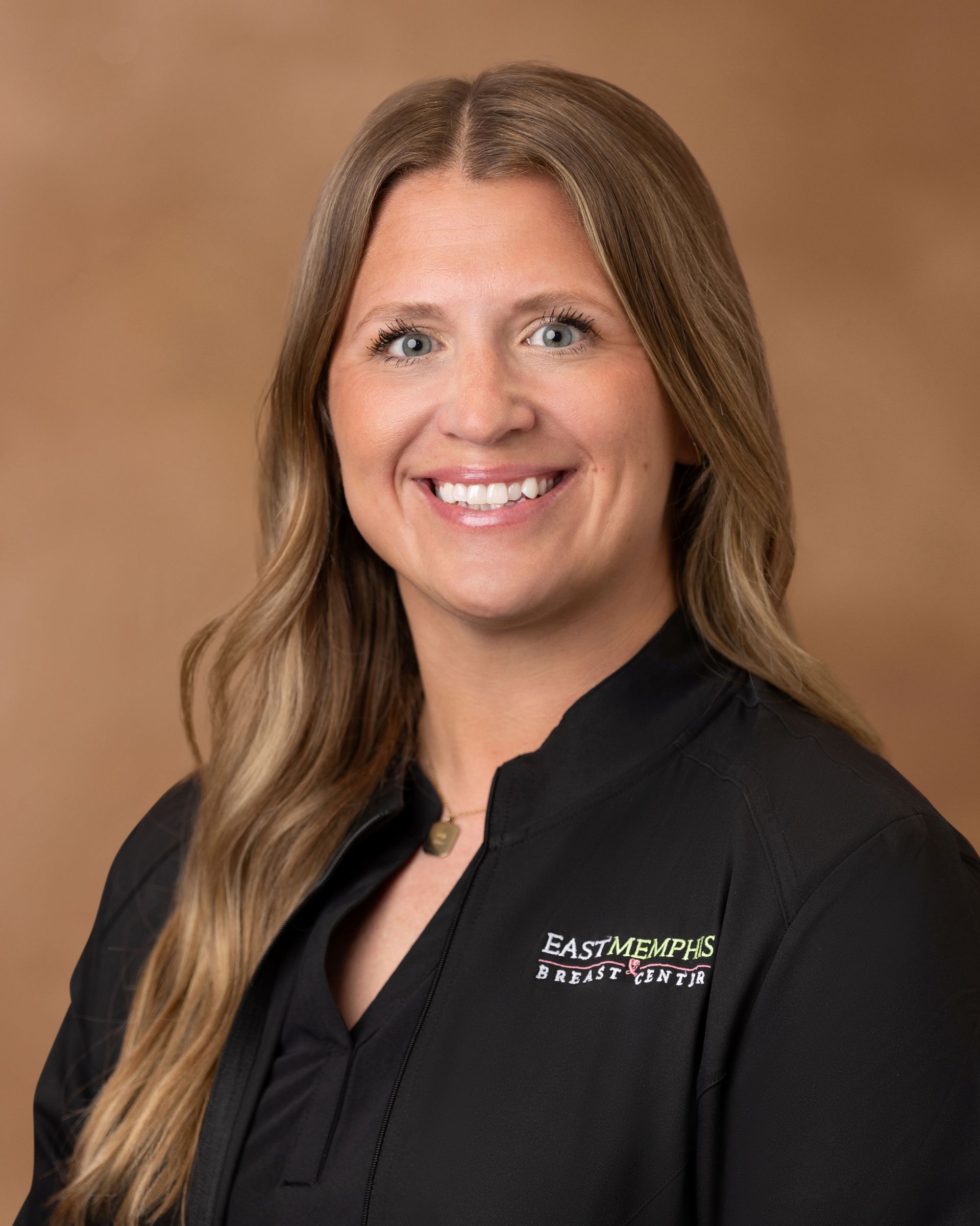 Smiling professional in black top against a brown studio background