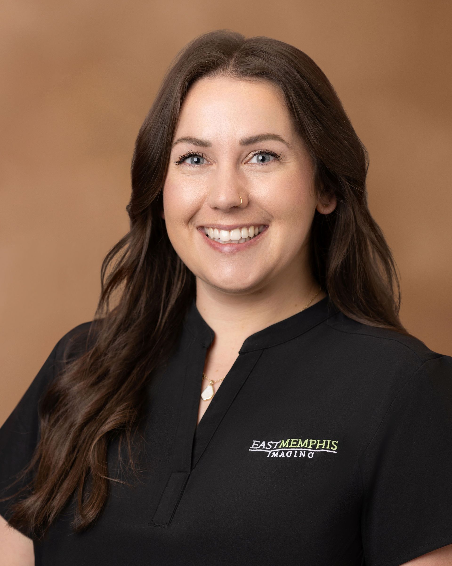 Smiling professional in a black shirt against a brown studio background