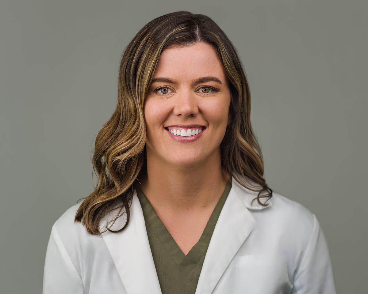A woman in a lab coat is smiling for the camera.