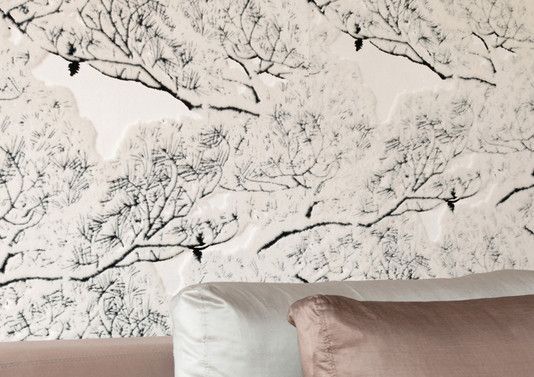 Ein Bett mit einer Blumentapete an der Wand dahinter