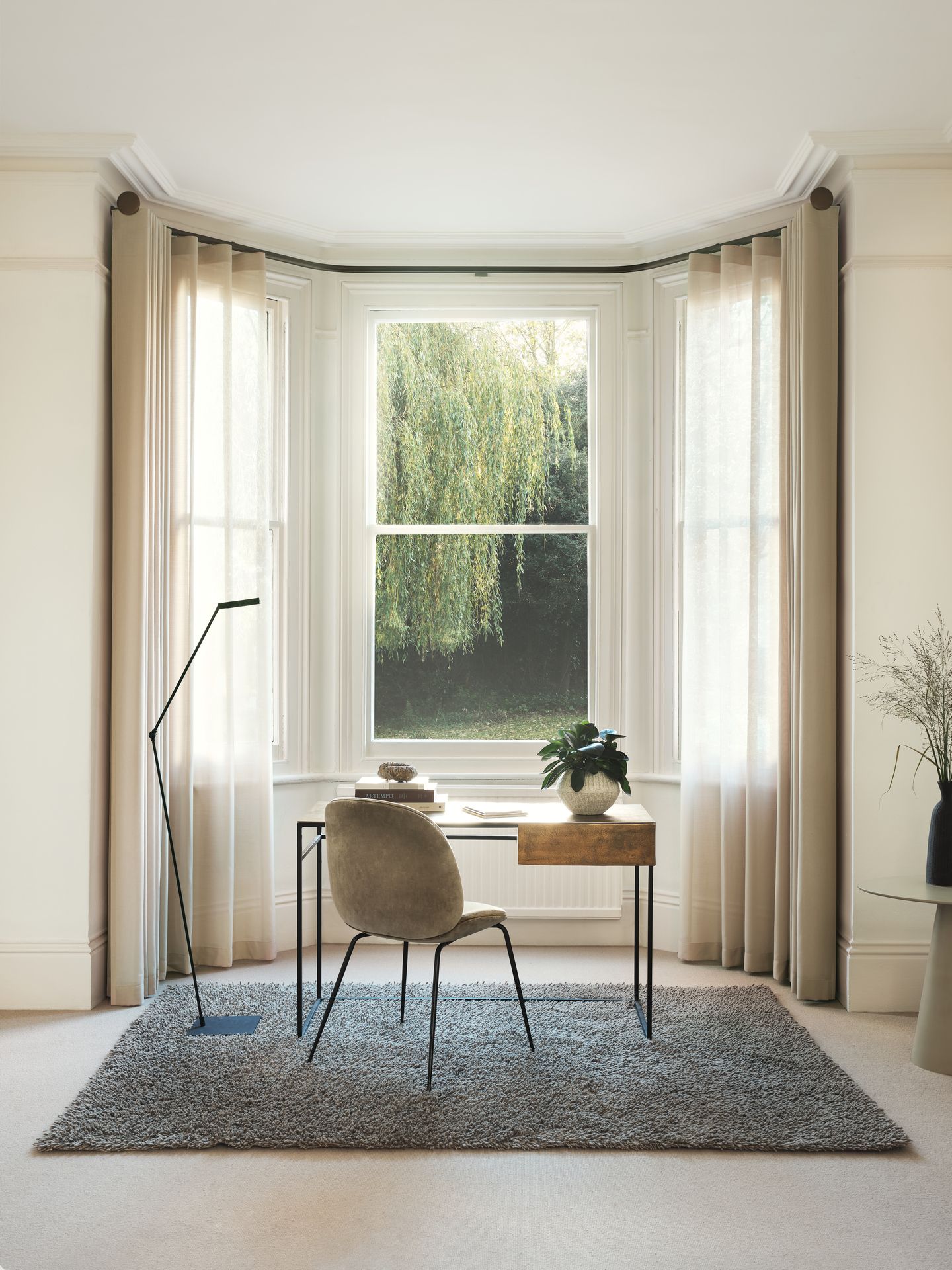 Ein Zimmer mit einem Schreibtisch und einem Stuhl vor einem Fenster.