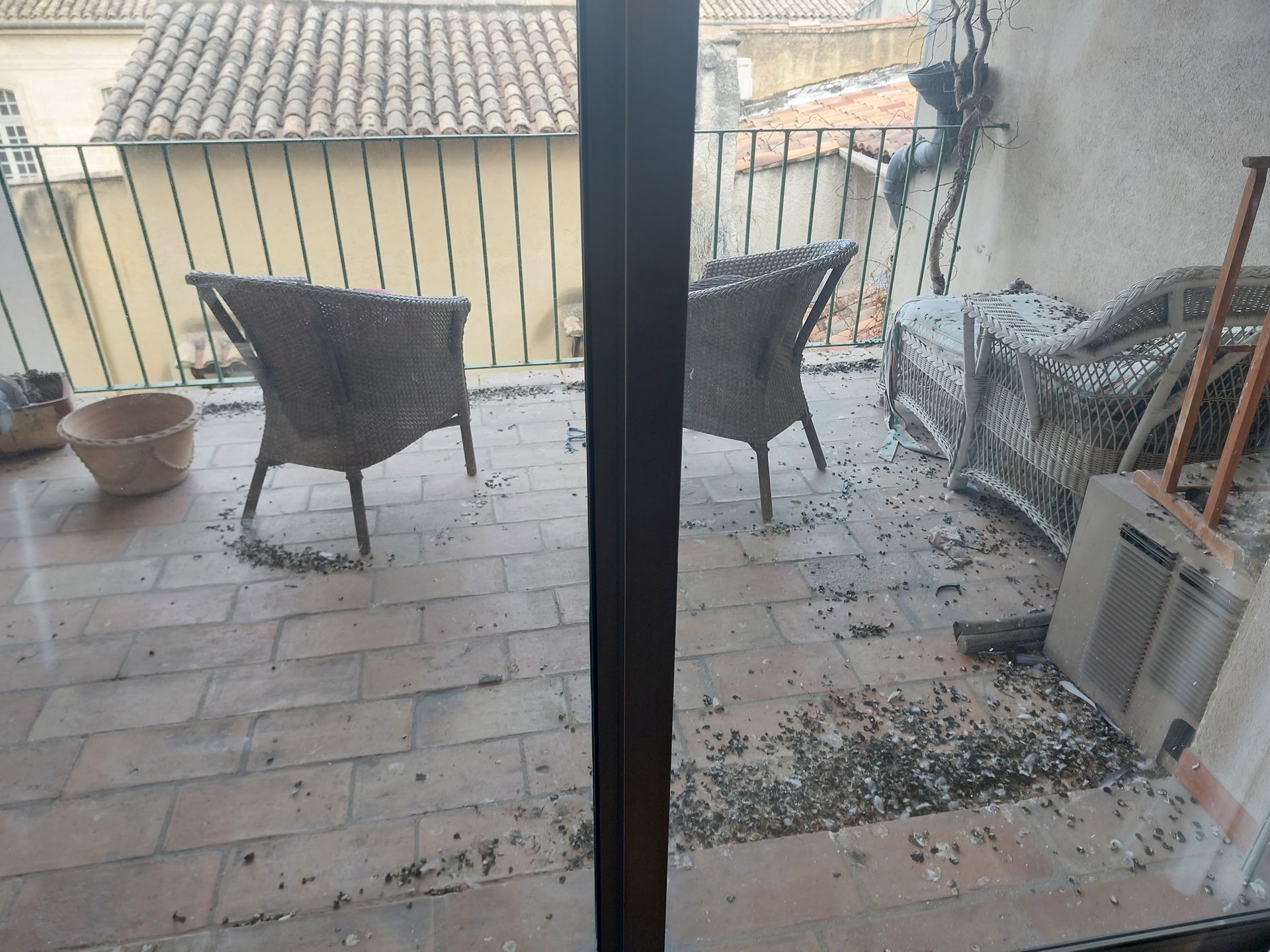 Deux chaises sont assises sur un balcon avec une porte coulissante en verre.