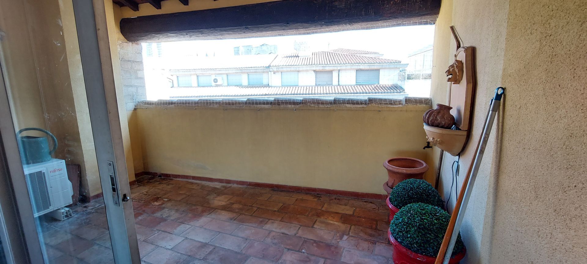 Un balcon avec une porte coulissante en verre et des plantes en pot.