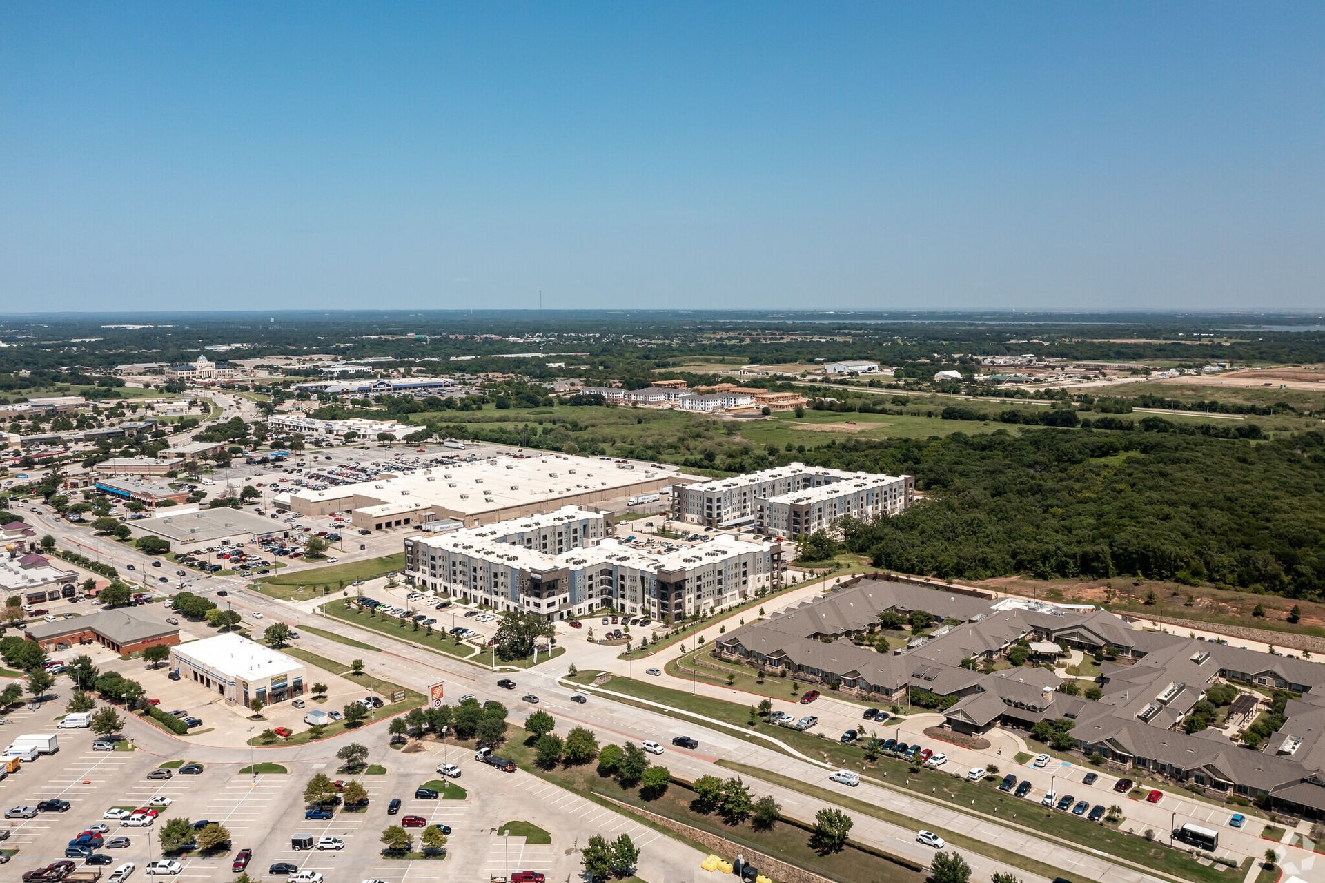 Aerial view of a large apartment complex with multiple buildings, parking lots, and surrounding green space.
