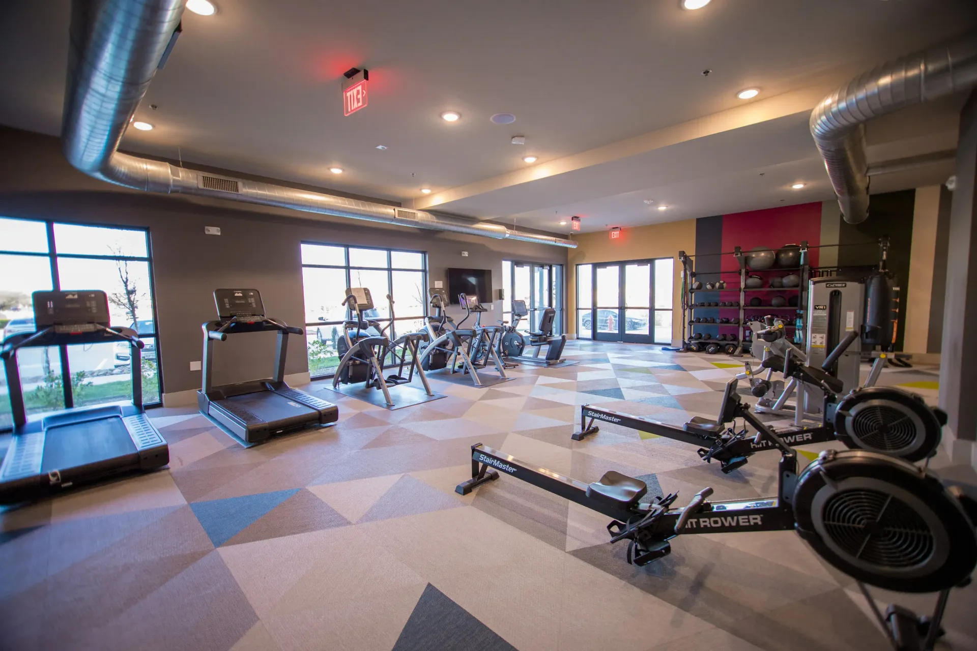 Indoor gym within the multifamily community featuring cardio machines and weights.