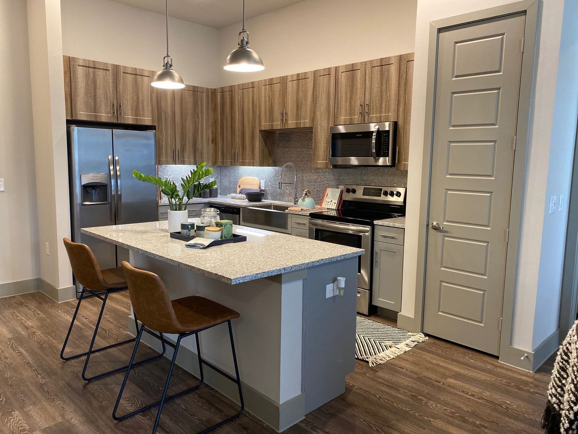 Modern apartment kitchen with an island, granite countertops, and stainless-steel appliances.