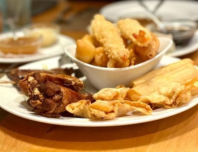 Assorted fried pastries and savory snacks on a white plate at a restaurant table
