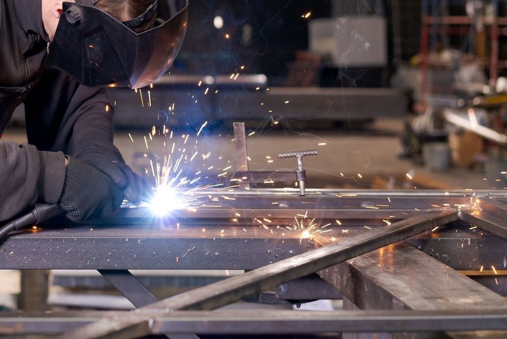 Welder in protective gear sparks metal frame in a workshop