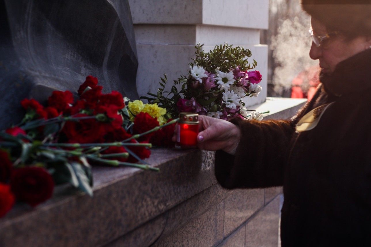Woman placing a memorial candle beside flowers during a remembrance service in Allentown, PA