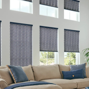 Living room with beige sectional sofa, blue pillows, and patterned navy window shades above large windows