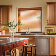 Modern kitchen with wooden cabinets, a central island, sink under window blinds, and stainless dishwasher