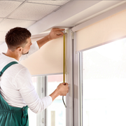 Worker measuring a window frame with a tape measure inside a bright room