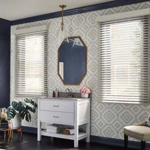 Stylish room with patterned wallpaper, two windows, gold mirror, white console, plant, and bench