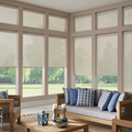 Bright sunroom with large windows, beige sofa, blue pillows, and view of green lawn outside