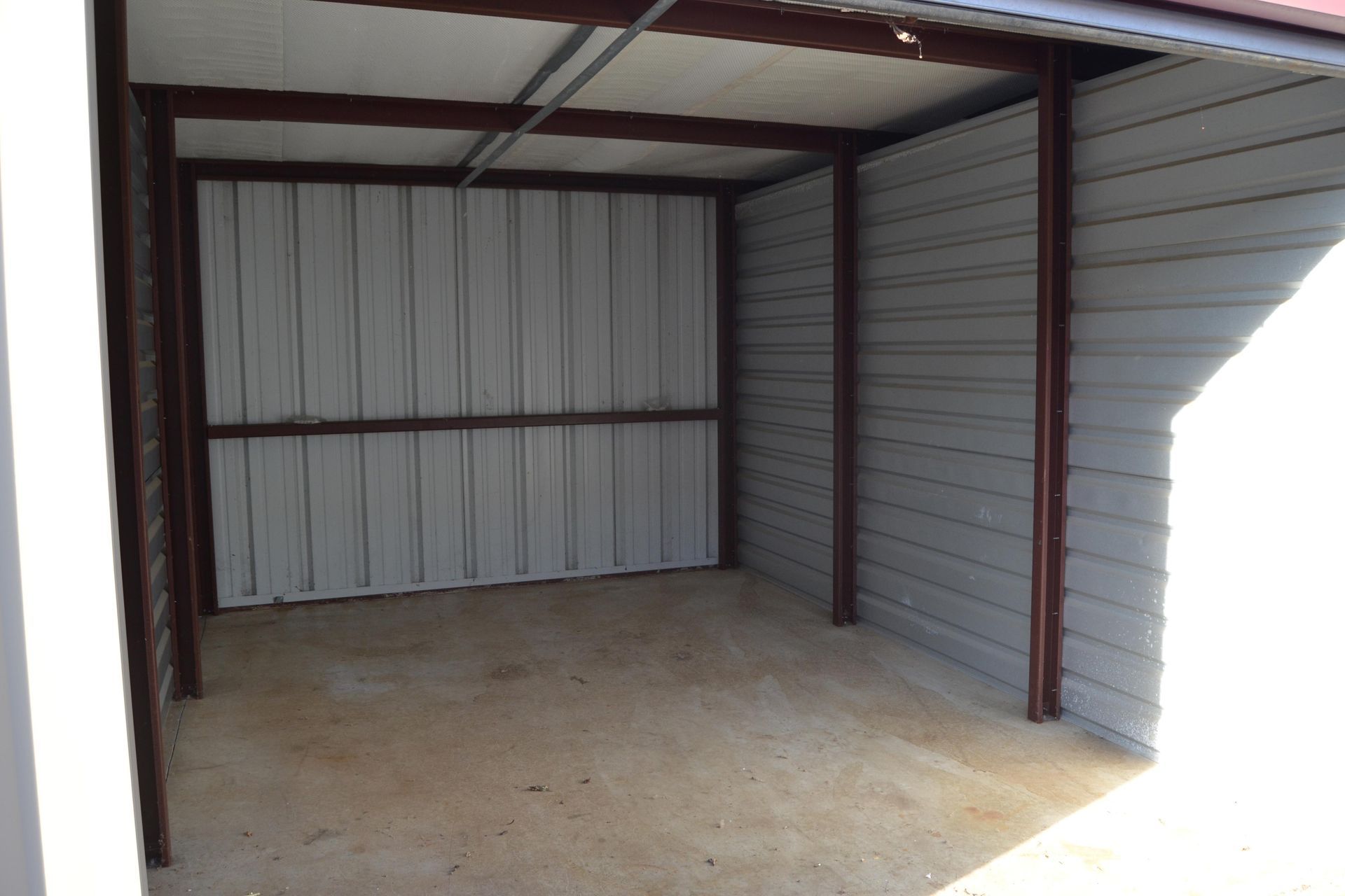 An empty garage with a metal roof and a concrete floor.