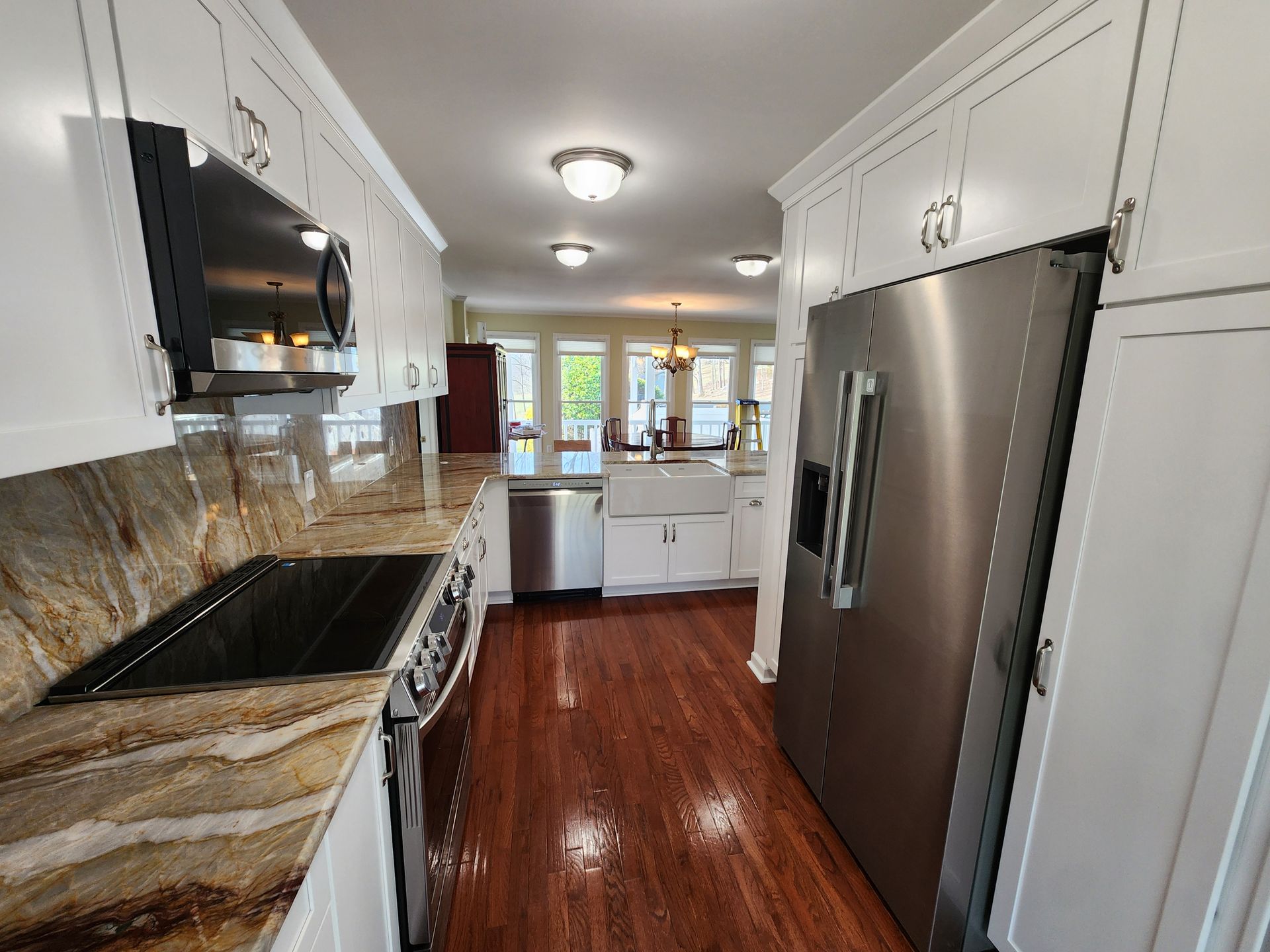 Kitchen with white cabinets, stainless steel appliances, and wood flooring.